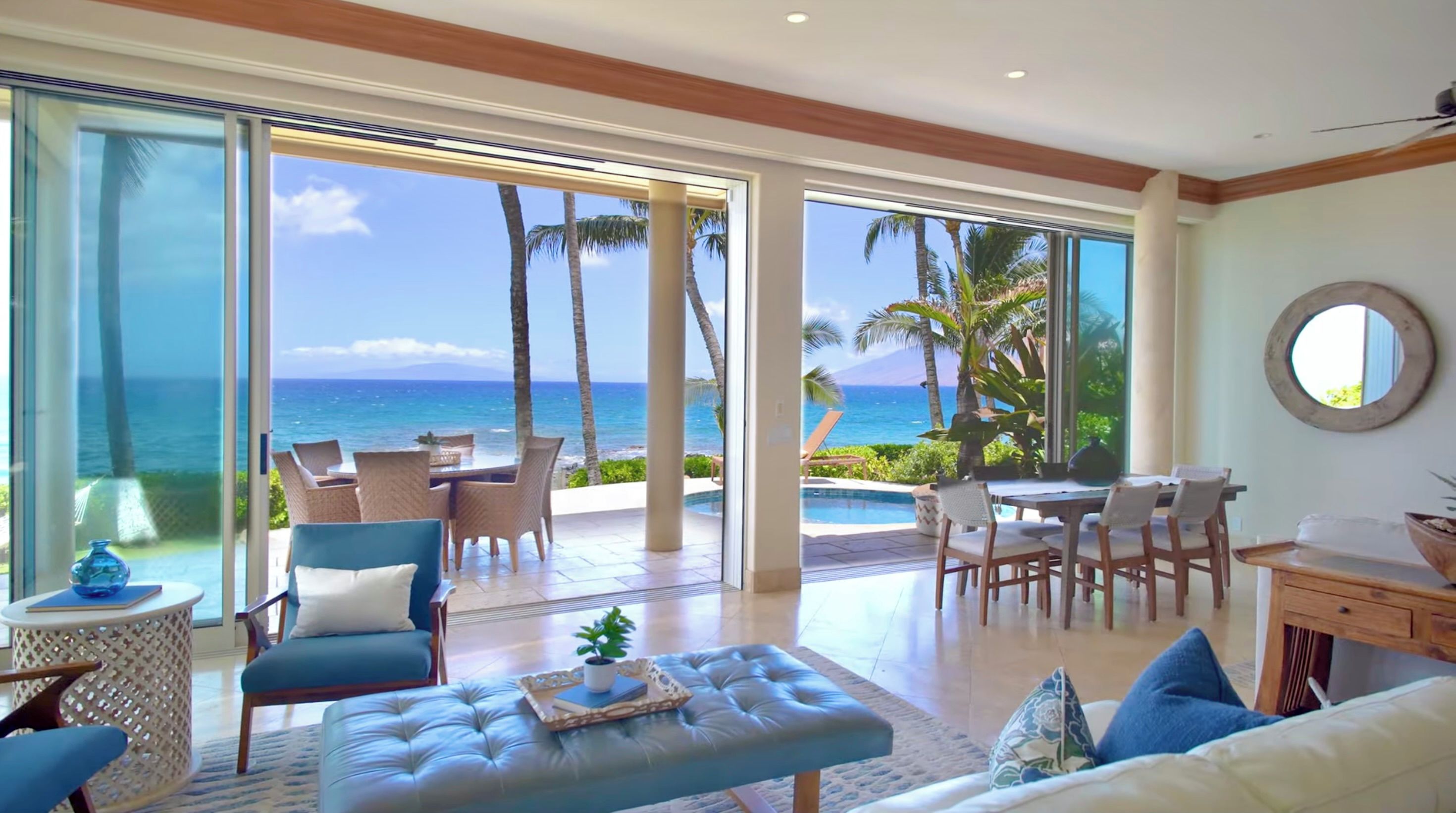 Amplia sala de estar con vista al océano, que incluye un sofá, sillas, una mesa de comedor y una zona junto a la piscina.