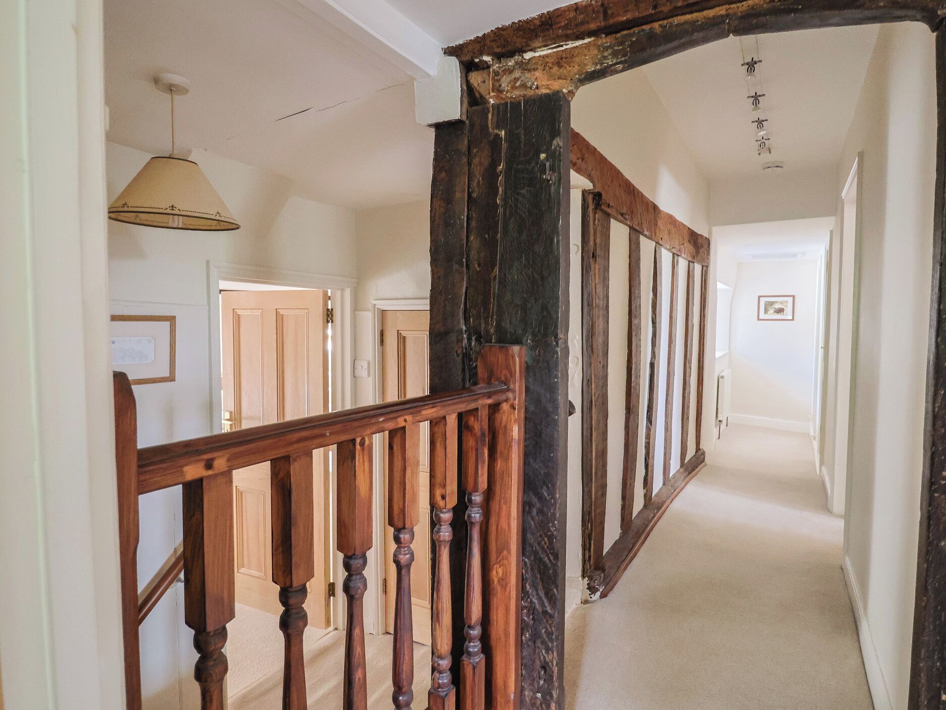 A hallway with wooden railings, a ceiling fan, and a door at the end.