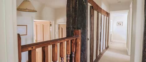 A hallway with wooden railings, a ceiling fan, and a door at the end.