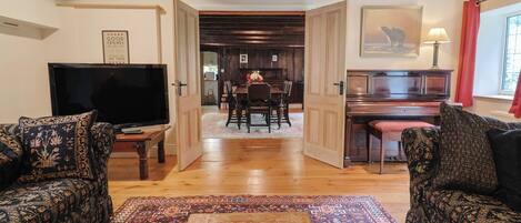 A living room with a television, sofa, coffee table, and a view into the dining area.