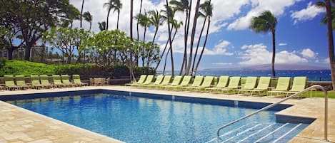 A swimming pool with lounge chairs and palm trees.