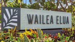 Un panneau portant l’inscription « WAILEA ELUA » et entouré de différentes plantes.