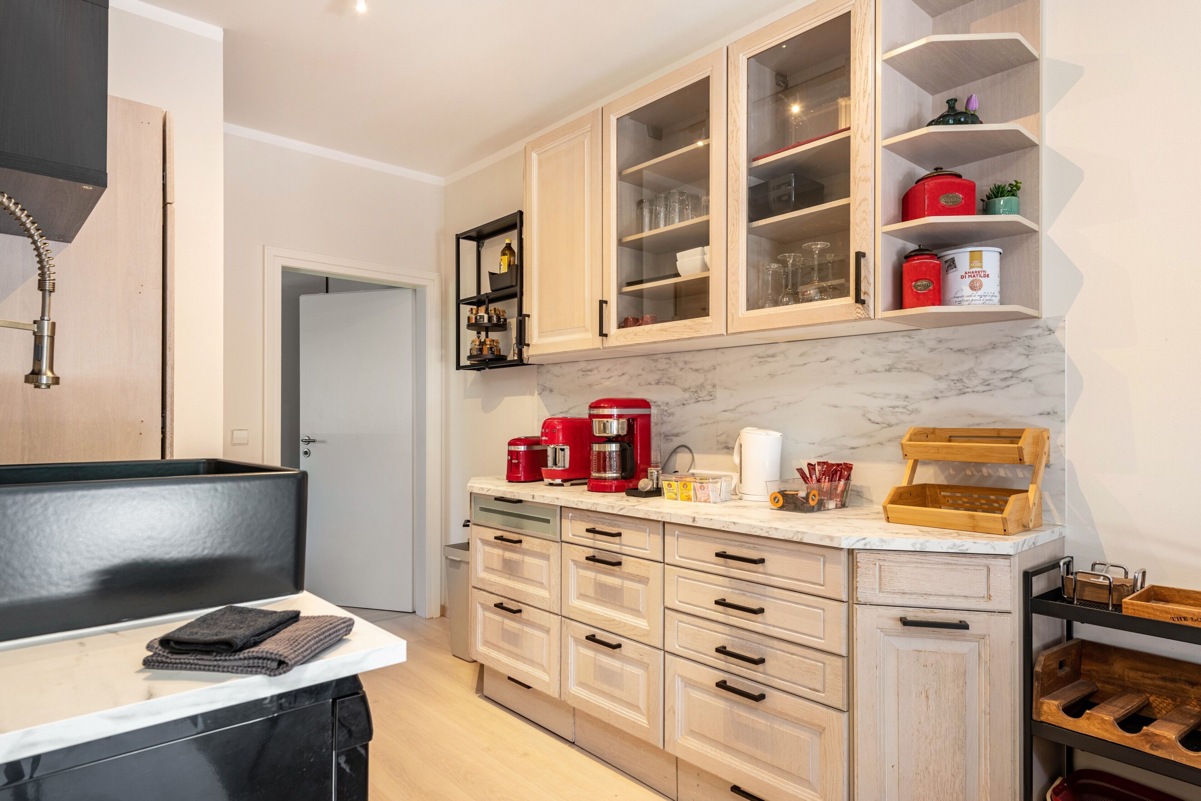 A kitchen with wooden cabinets, a marble countertop, and various appliances.