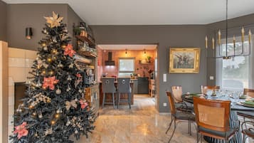 A modern kitchen with a dining area, a Christmas tree, and a large window.