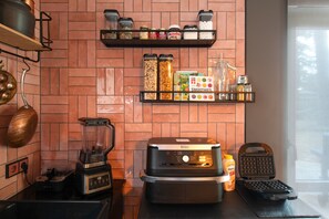 A kitchen with a brick backsplash, a blender, a waffle maker, and various food items on shelves. - Luxury Lakeside Retreat Villa for 11 – Festive Forest Getaway Fireplace & Workspaces, 20 Mins to BER (Bestensee)