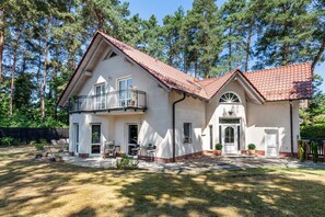 A two-story house with a balcony, a front door, and a small porch area. - Luxury Lakeside Retreat Villa for 11 – Sandy Beach & 20 Mins to BER (Bestensee)