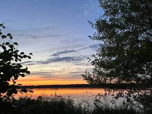 A serene lakeside view with trees framing the scene. - Boutique Beach Villa for Groups – Wellness, Garden Dining & Lakes near Berlin (Bestensee)