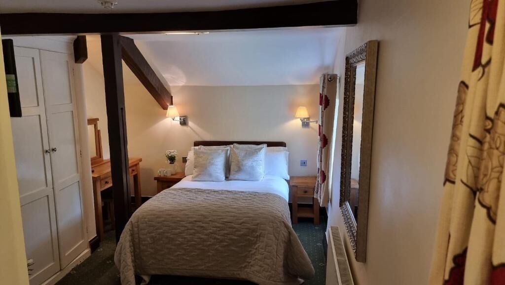 Un dormitorio con cama, mesitas de noche, un espejo y una puerta.