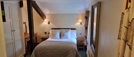Un dormitorio con cama, mesitas de noche, un espejo y una puerta.