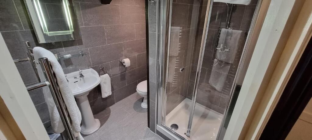 Un baño con cabina de ducha de vidrio, un lavamanos y un inodoro.