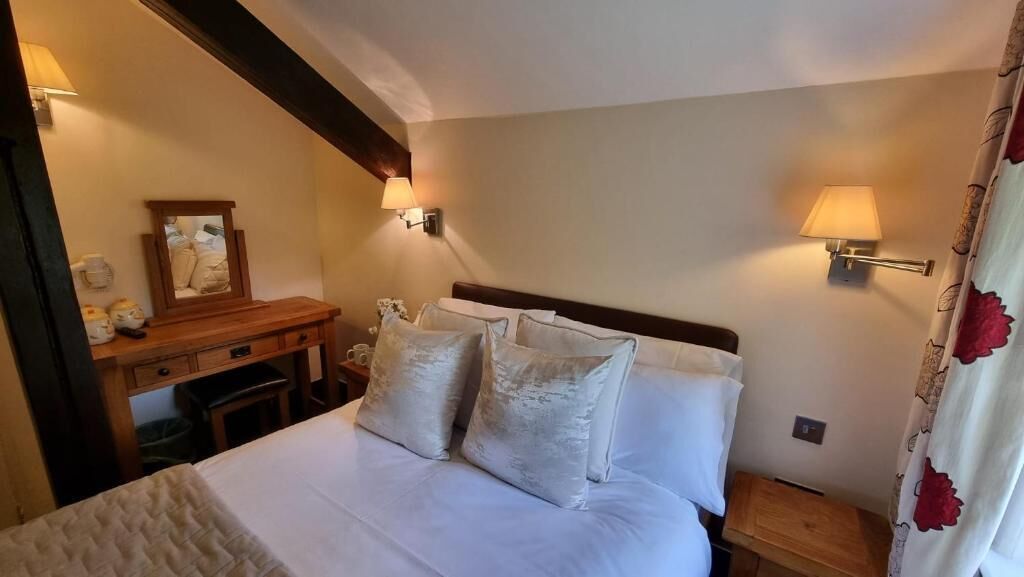 Een hotelkamer met een bed, nachtlampjes, een bureau en een spiegel.