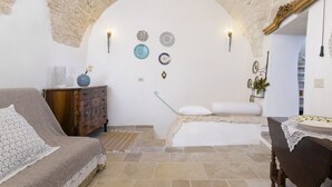Una habitación acogedora con un arco de piedra, un sofá, un aparador de madera y una mesa de comedor con un plato.