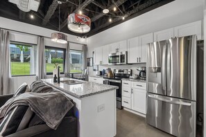 Een moderne keuken met roestvrijstalen apparatuur, witte kasten en een groot eiland.