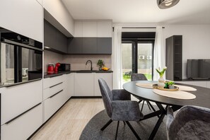 Eine moderne Küche mit Essbereich, inklusive Tisch mit Stühlen und einem Fernseher.