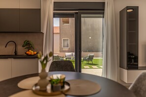 Eine moderne Küche mit Essbereich, Blick auf die Terrass und einer Schiebetür.