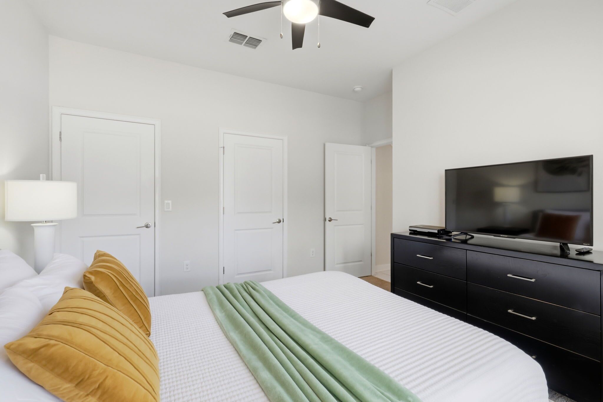Ein Schlafzimmer mit einem Bett, einem Fernseher, einer Kommode und einem Deckenventilator.