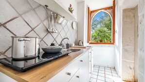 Una cocina con estufa, lavamanos y ventana con vistas al verdor.