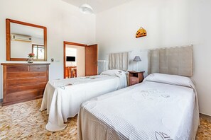 Una habitación con dos camas, un aparador de madera, un espejo, un radiador y una lámpara.