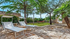 An outdoor patio with lounge chairs, a hammock, and a stone-tiled floor. - Casolare Di Puglia With Private Pool (Noci)
