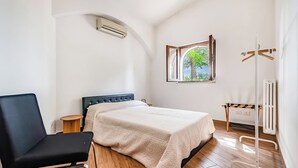 A bedroom with a bed, a chair, a radiator, and a window with a view of trees. - Casolare Di Puglia With Private Pool (Noci)