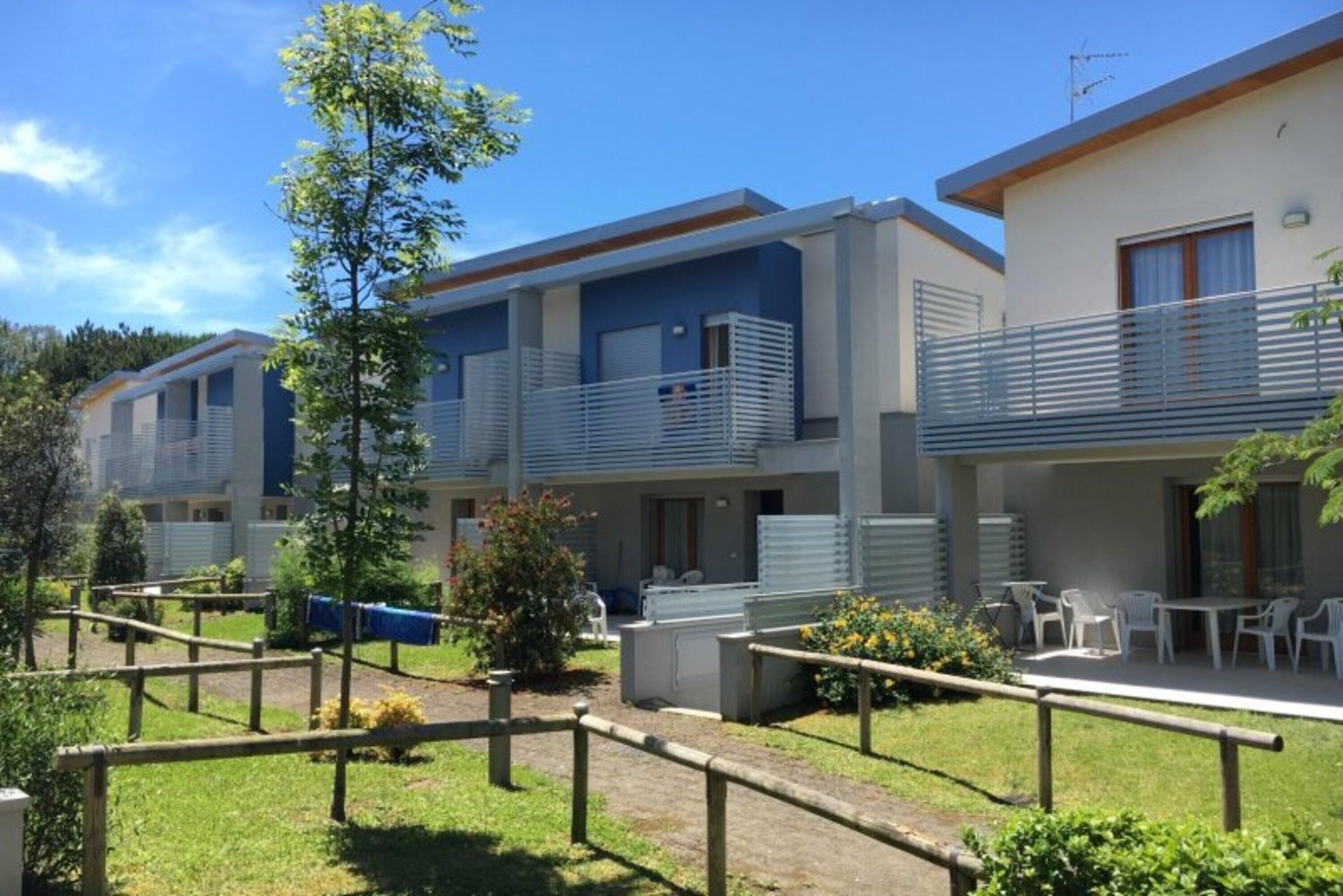A row of modern, two-story cabins with balconies, outdoor seating, and a well-maintained garden area.