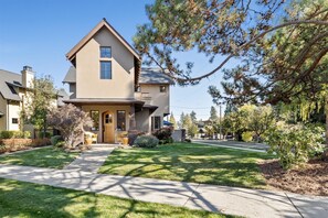 A two-story house with a front porch, a driveway, and surrounding greenery. - New! Luxury Bend Retreat Steps From Downtown & River (Bend)