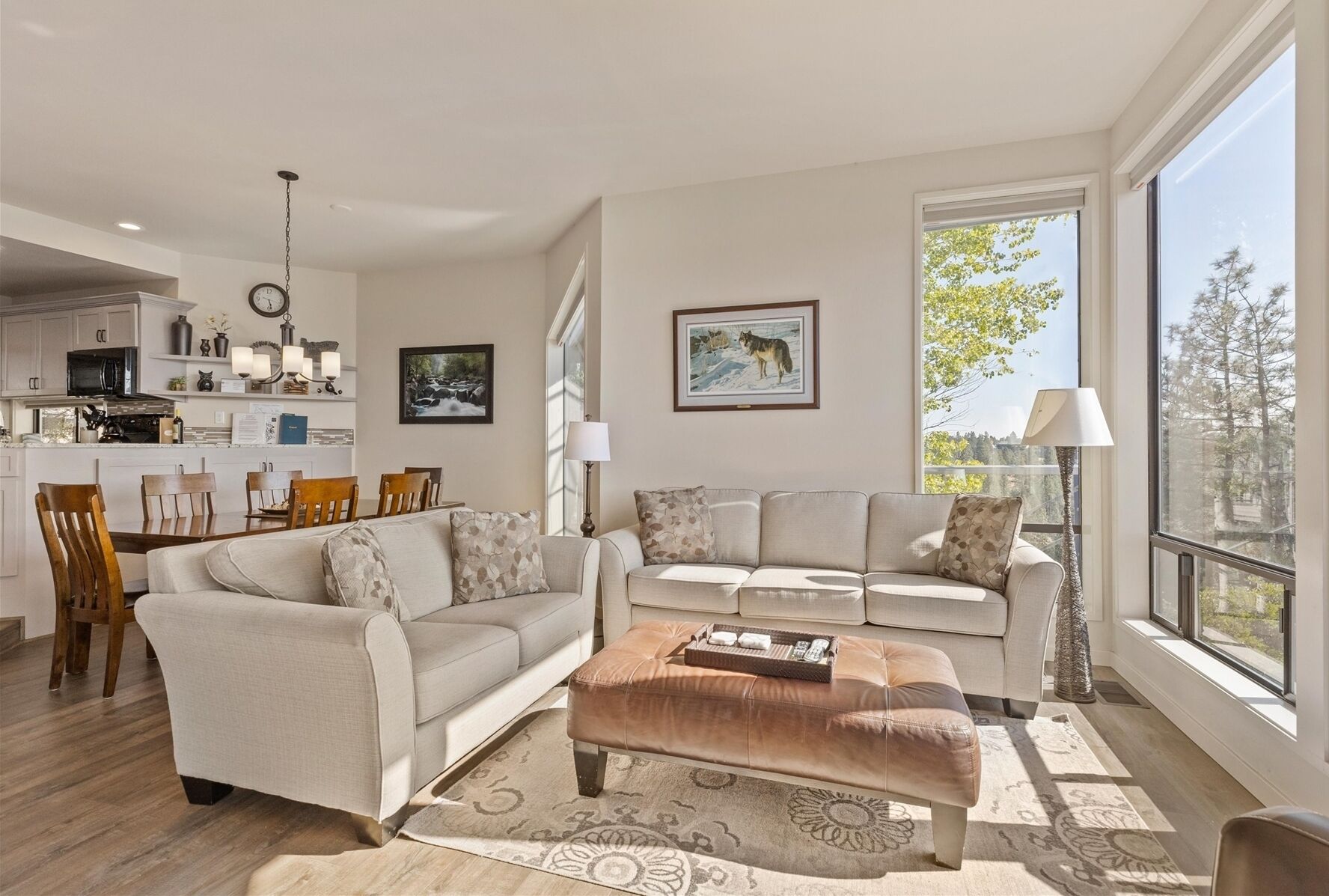 A modern living room with a sofa, ottoman, and dining area.