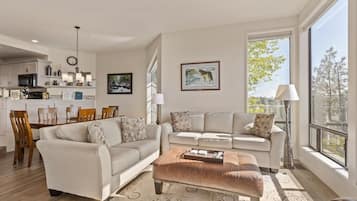 A modern living room with a sofa, ottoman, and dining area.