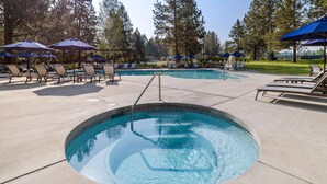 A swimming pool with lounge chairs and umbrellas, surrounded by trees. - New! Cozy Bend Escape | Hot Tub | Forest Views (Bend)