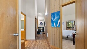 A hallway with wooden flooring leading to a room with a bed and a window. - New! Cozy Bend Escape | Hot Tub | Forest Views (Bend)