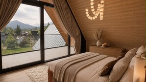 A bedroom with a large window, wooden ceiling, and a bed with a nightstand.