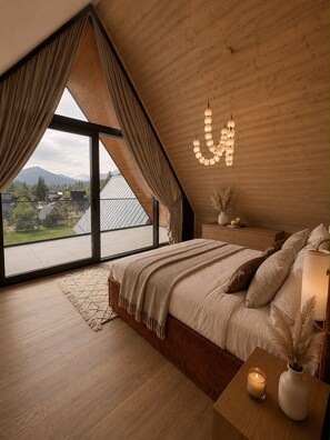 Un dormitorio con un ventanal grande, techo de madera y una cama con mesita de noche.