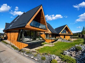 A modern wooden house with large windows and a sloped roof.