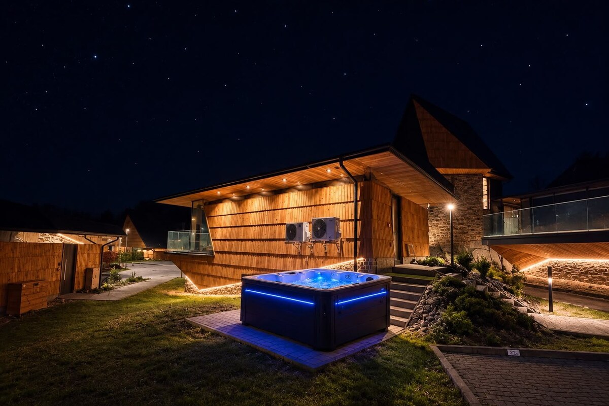 A modern house with a hot tub in the yard, wooden exterior, and a stone wall.