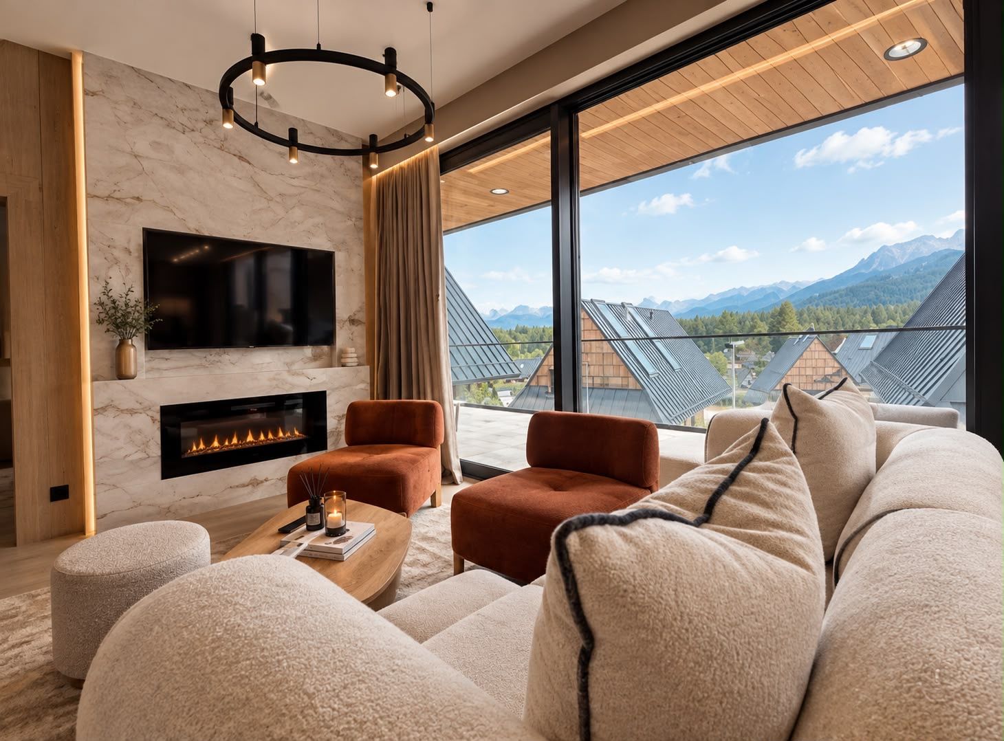 A modern living room with a fireplace, comfortable seating, a large TV, and a view of mountains.