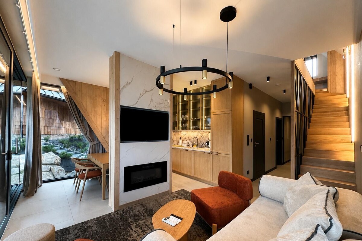 Un salon moderne avec une cheminée, un coin repas et une cuisine dotée de meubles en bois.