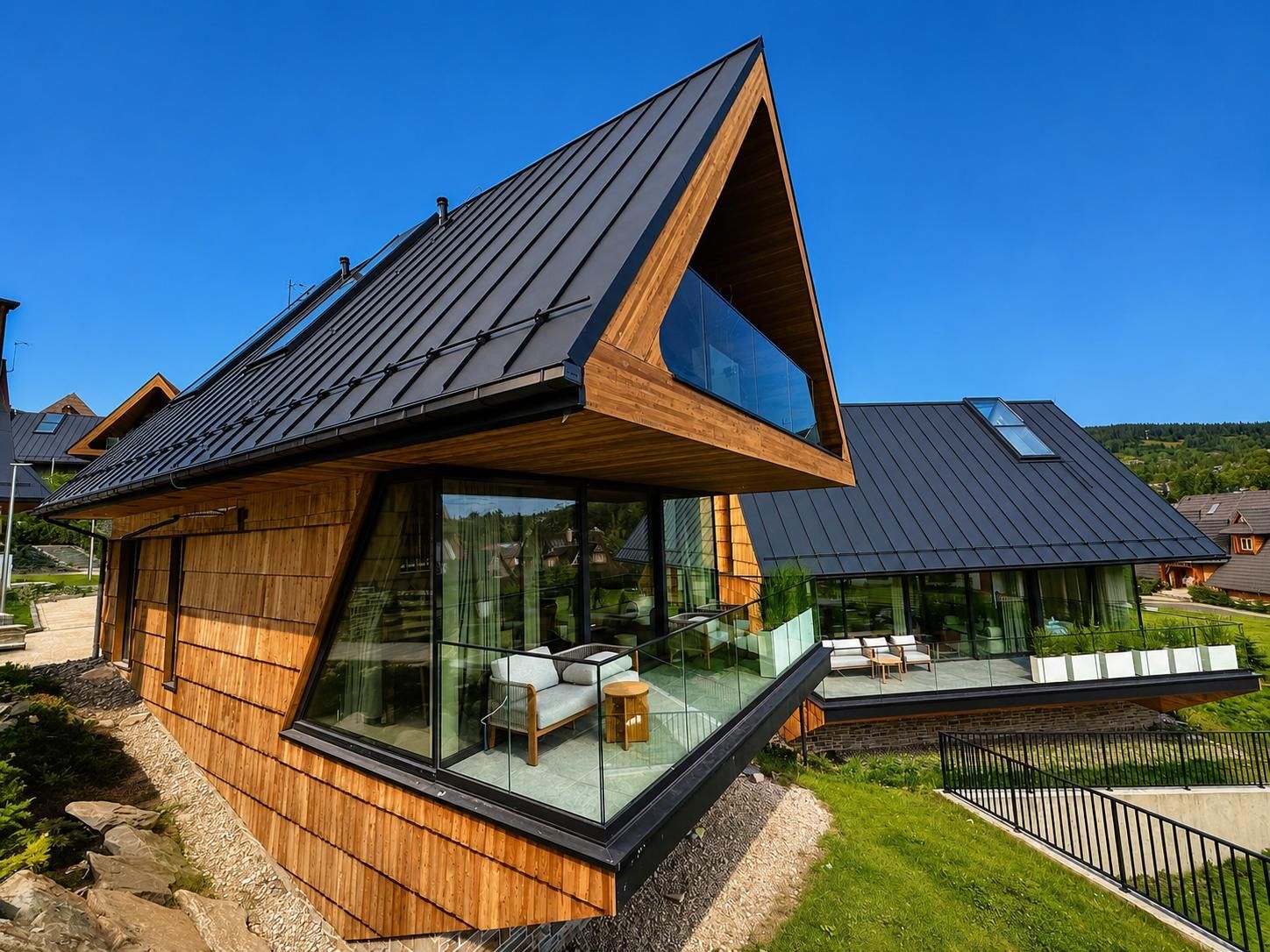 A modern house with a sloped roof, large glass windows, and a wooden exterior.
