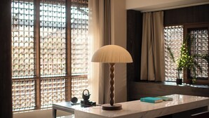 A room with a marble table, a lamp, a small shelf with books, and a window with a lattice design. - Windy Wan Gang Wind Listening Art Hotel (Lijiang)