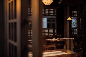 Een traditionele Japanse kamer met tatami vloerbedekking, schuifdeuren en een lage tafel met stoelen.