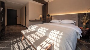 A modern hotel room with a large bed, a bench, a nightstand, and a wall-mounted lamp. - Windy Wan Gang Wind Listening Art Hotel (Lijiang)