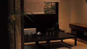 A dimly lit room with a table set for tea, a painting on the wall, and a sofa with cushions. - Windy Wan Gang Wind Listening Art Hotel (Lijiang)