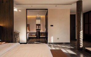 A hotel room with a bed, a wooden cabinet, a bathroom with a mirror, and a large pillar. - Windy Wan Gang Wind Listening Art Hotel (Lijiang)