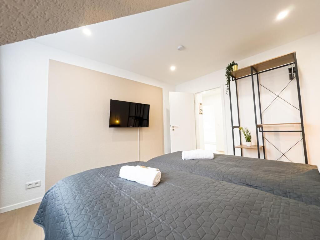 Een hotelkamer met twee bedden, een aan de muur bevestigde televisie en een kledingkast met schuifdeuren.