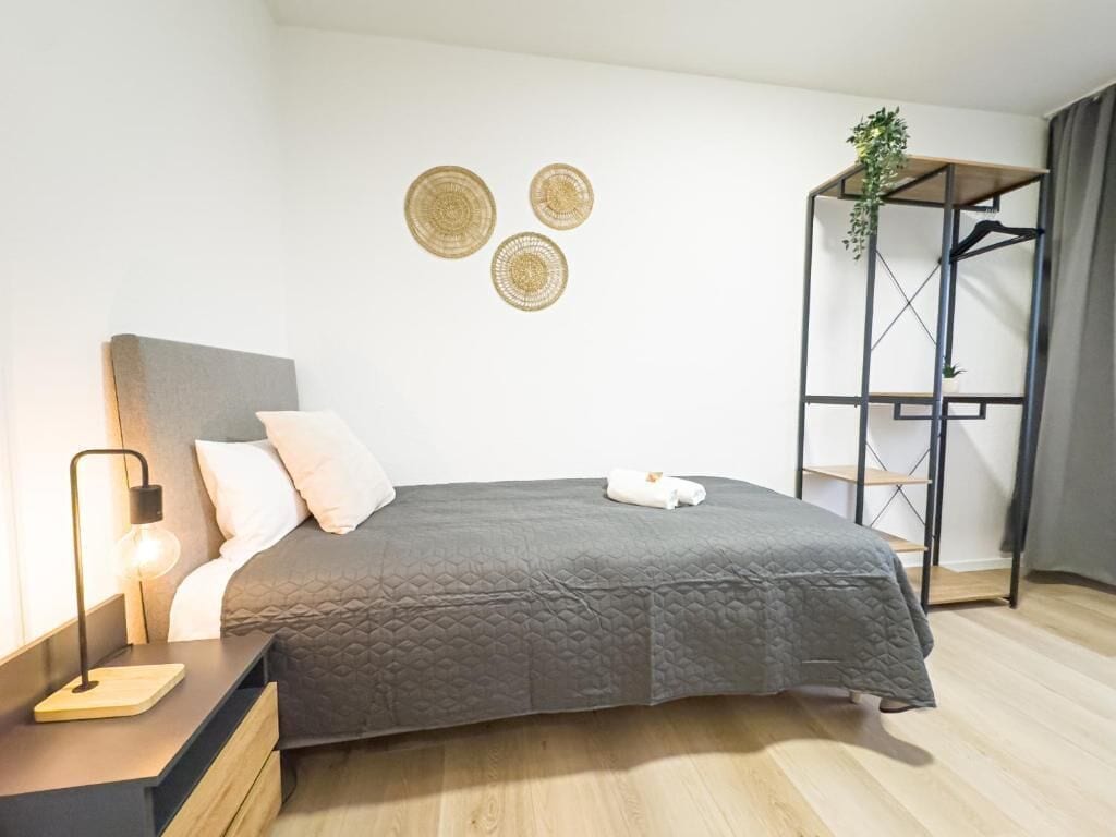 Un dormitorio moderno con cama, mesita de noche, lámpara y decoración en la pared.