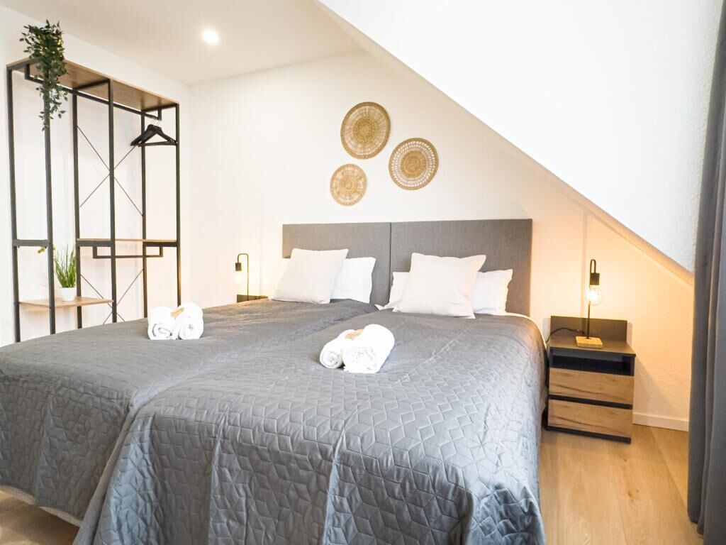 A modern bedroom with a large bed, bedside tables, and decorative wall art.