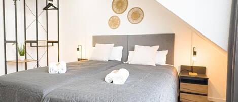 A modern bedroom with a large bed, bedside tables, and decorative wall art.