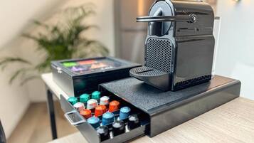 Eine Kaffeemaschine mit einer Schublade, die farbige Kapseln, ein kleines Display und eine Metallplatte enthält.