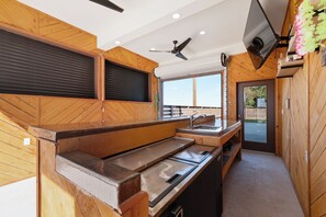 Une cuisine avec des murs en bois, un ventilateur de plafond et une grande fenêtre.