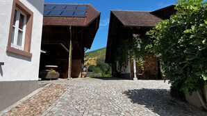 A cobblestone street leading to a building with a sloped roof and solar panels. - Cozy Black Forest Studio (52 sqm) – Free Wi-Fi & Parking, Close to Town (Gengenbach)