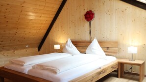 A wooden-paneled room with a bed, two bedside tables, and a wall-mounted red flower decoration. - Cozy Black Forest Studio (52 sqm) – Free Wi-Fi & Parking, Close to Town (Gengenbach)